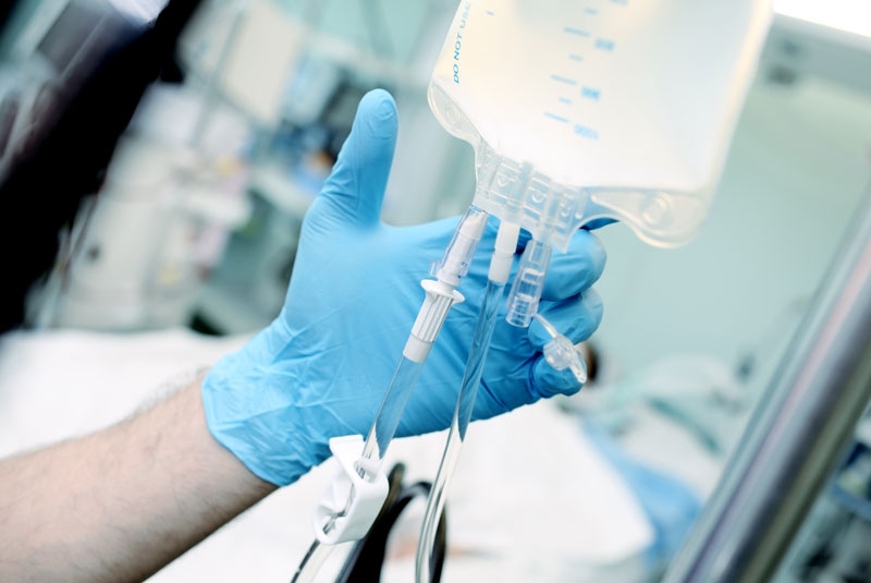 a dentist's hand setting up a dental IV bag for sedation.